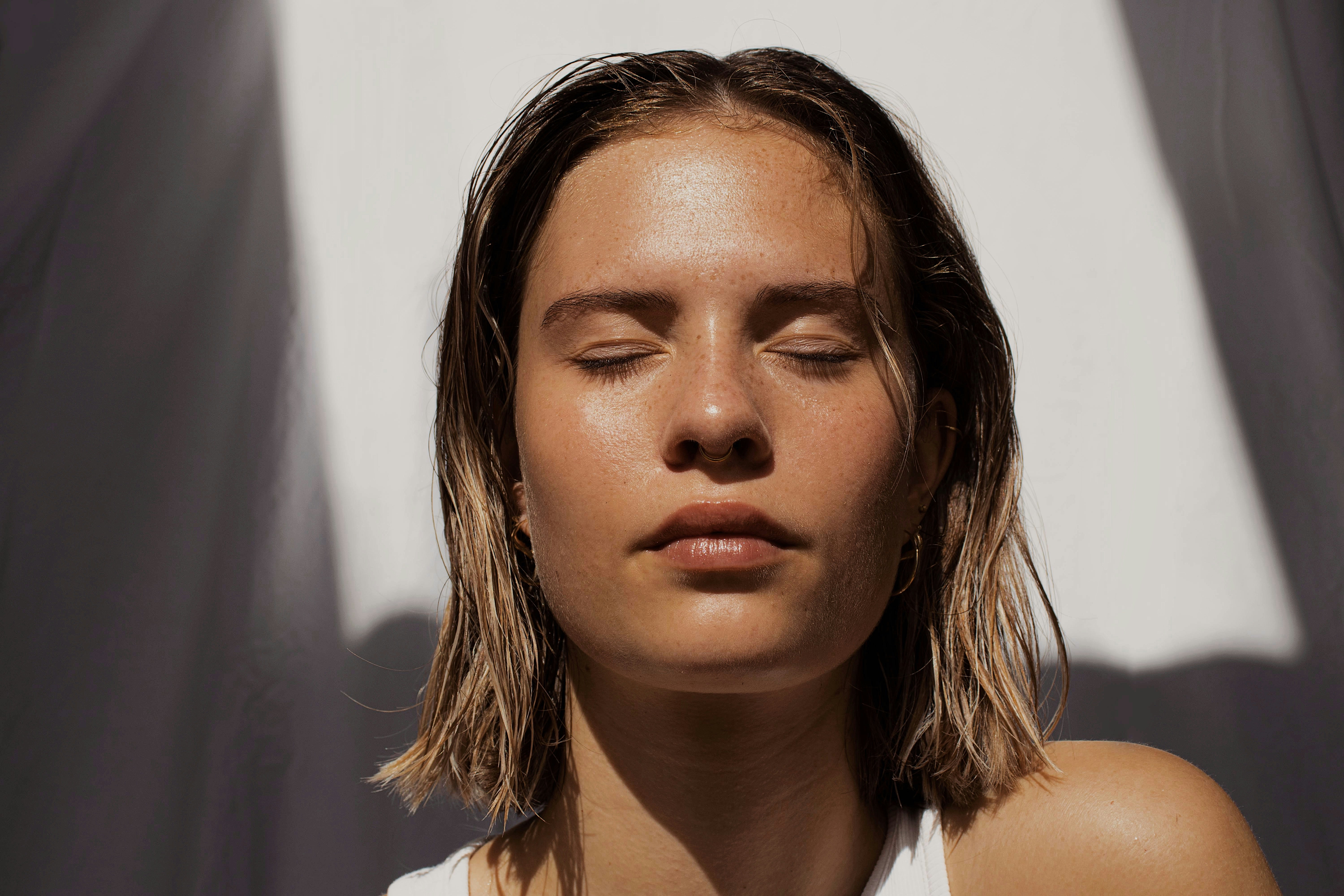 woman with short blonde hair closing her eyes in the sum
